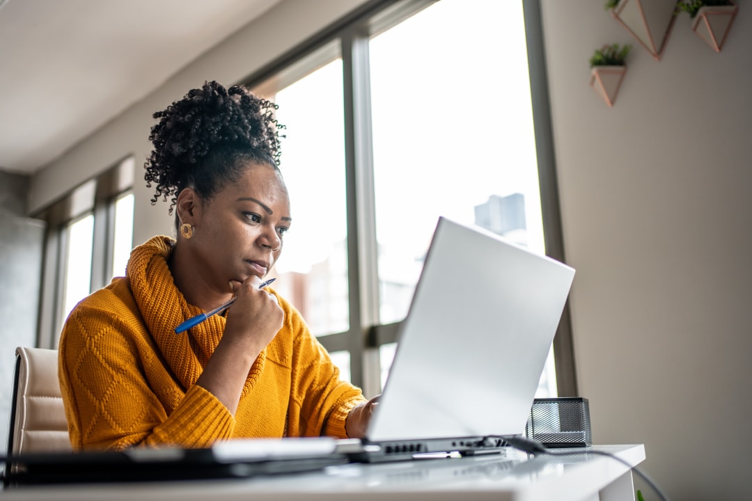 Women thinking, working on a laptop with pencil in hand